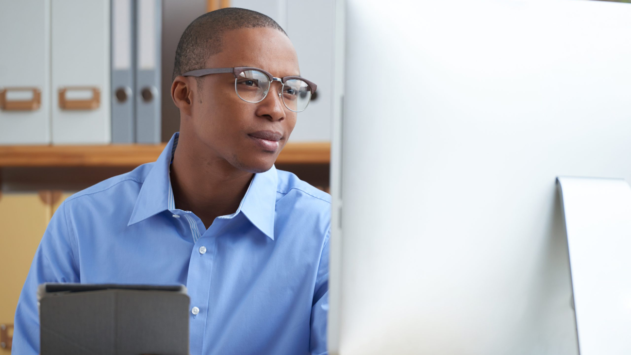 Smiling office worker reading news on computer screen