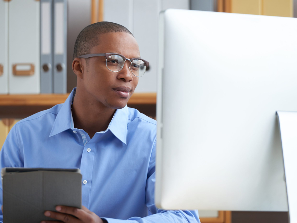 Smiling office worker reading news on computer screen